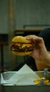 Hands holding homemade beef grill bacon cheese with salad hamberger and French fries