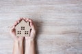 Hands holding house model on wood table background with copy space. Financial, money, refinance, Real estate and new home concept