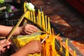 Hands holding incense sticks, lighting from the burning yellow candle. Traditional Thailand buddhist concept