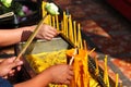 Hands holding incense sticks, lighting from the burning yellow candle. Traditional Thailand buddhist concept Royalty Free Stock Photo