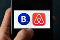 Hands holding iPhone 11 with Airbnb and booking.com service icons.