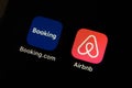 Hands holding iPhone 11 with Airbnb and booking.com service icons.