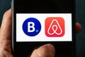 Hands holding iPhone 11 with Airbnb and booking.com service icons.