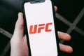 Hands holding iPhone with UFC logo on the screen.