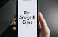 Hands holding iPhone X with The New York Times logo on the screen. Royalty Free Stock Photo