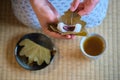 Hands holding japanese Kashiwa mochi filled with anko, and green tea on tatami. Royalty Free Stock Photo