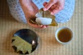 Hands holding japanese Kashiwa mochi and green tea on tatami.