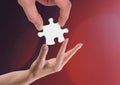 Hands holding jigsaw piece helping against red background Royalty Free Stock Photo