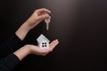 Hands holding keys and a model of a white wooden house on a black background. Copyspace Royalty Free Stock Photo