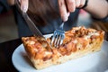 Hands holding knife and folk to cut bacon and cheese bread in a white plate Royalty Free Stock Photo