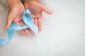 Hands holding light blue color ribbon on white fabric background with copy space. Lymphedema and Prostate Cancer Awareness month Royalty Free Stock Photo