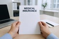 Hands holding medical insurance document in modern office setting for professional paperwork and organization. concept of Royalty Free Stock Photo