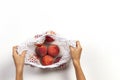 Hands holding mesh glocery shopping bag with fresh peaches on white background. Top view Royalty Free Stock Photo