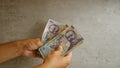Hands holding multiple romanian 100 lei banknotes against a concrete background Royalty Free Stock Photo