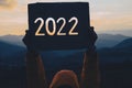 Hands holding of new year 2022 silhouette design from cardboard against the background of mountain with sunset. Happy New Year Royalty Free Stock Photo