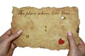 Hands holding old parchment with the inscription `The place where love lives`