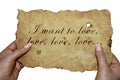 Hands holding old parchment with the words `I want to love, love, love ...`