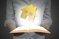 Hands holding open book with golden house Royalty Free Stock Photo