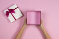 Hands holding open empty present gift box on pastel pink background, top view Royalty Free Stock Photo