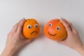 Hands holding orange and grapefruit with funny faces on white background. Pessimist and optimist concept Royalty Free Stock Photo