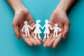 Hands holding paper cut outs of family