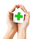 Hands holding paper house with green cross Royalty Free Stock Photo