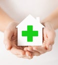 Hands holding paper house with green cross Royalty Free Stock Photo