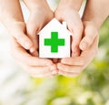 Hands holding paper house with green cross Royalty Free Stock Photo