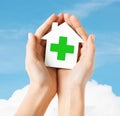 Hands holding paper house with green cross Royalty Free Stock Photo