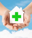 Hands holding paper house with green cross Royalty Free Stock Photo