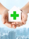 Hands holding paper house with green cross Royalty Free Stock Photo