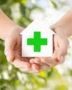 Hands holding paper house with green cross Royalty Free Stock Photo