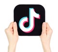 Hands holding paper TikTok mobile app icon, on transparent background. TikTok is a short-form video hosting service owned by Royalty Free Stock Photo