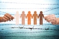 Hands holding people pictogram over barb wire Royalty Free Stock Photo