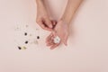 Hands holding perfume samples and white flowers on pink background. Top view. Copy space.