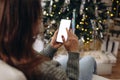 hands holding phone with empty screen on background of golden beautiful christmas tree with lights in evening