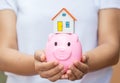 Hands holding a piggy bank and a house model. Royalty Free Stock Photo