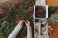 Hands holding pine cone and green fir branches on wooden table, making rustic christmas wreath Royalty Free Stock Photo