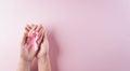 Hands holding pink ribbon, Breast cancer awareness, symbolic bow color raising awareness on women`s breast tumor. Healthcare and Royalty Free Stock Photo