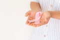 Hands holding pink ribbon curl on white isolated background with copy space. Breast cancer Awareness, male breast cancer disease, Royalty Free Stock Photo