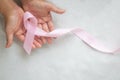 Hands holding pink ribbon curl on white isolated fabric with copy space. Breast cancer Awareness, male breast cancer disease, Royalty Free Stock Photo