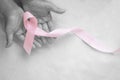 Hands holding pink ribbon curl on white isolated fabric with copy space. Breast cancer Awareness, male breast cancer disease, Royalty Free Stock Photo