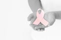 Hands holding pink ribbon curl on white isolated fabric with copy space. Breast cancer Awareness, male breast cancer disease, Royalty Free Stock Photo