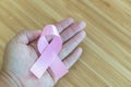 Hands holding pink ribbons on wood background, Breast cancer awareness and February Pink day Royalty Free Stock Photo
