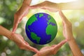 Hands holding planet earth on blurred green bokeh nature with warm sunlight background Royalty Free Stock Photo