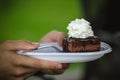 Hands holding plate with chocolate cake amandine