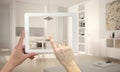 Hands holding and pointing on tablet showing modern kitchen. Blurry minimalist white kitchen in the background, architecture inter Royalty Free Stock Photo