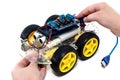 Hands holding programmable robotic car with obstacle avoidance and line following ability, on white background with