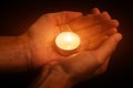 Hands holding and protecting glowing lit or burning candle candlelight on darkness Royalty Free Stock Photo