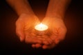 Hands holding and protecting glowing lit or burning candle candlelight on darkness Royalty Free Stock Photo